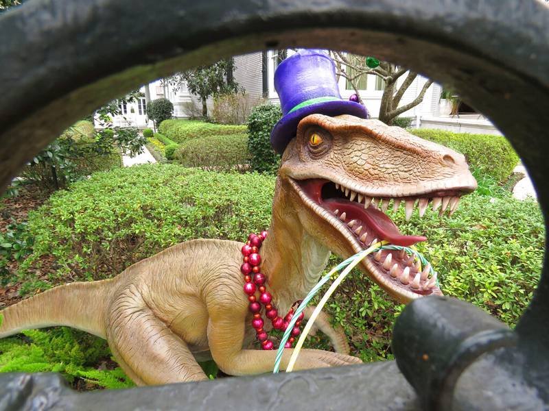 A top-hatted dinosaur, shown Tuesday, Jan. 26, 2021, is among Mardi Gras decorations in the yard of a mansion on St. Charles Avenue in New Orleans. Because pandemic dangers from large and widespread crowds have canceled Mardi Gras parades in New Orleans this year, thousands of people are decorating their homes as floats.