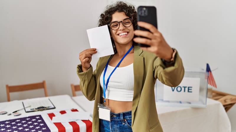 Young woman holding ballot taking a selfie