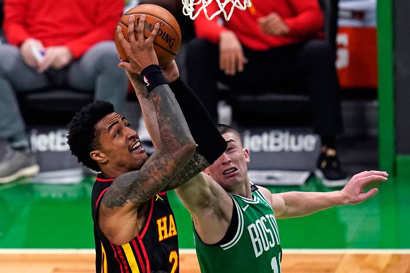 Atlanta Hawks forward John Collins, left, drives to the basket against Boston Celtics guard Payton Pritchard, right, during the first half, Wednesday, Feb. 17, 2021, in Boston.