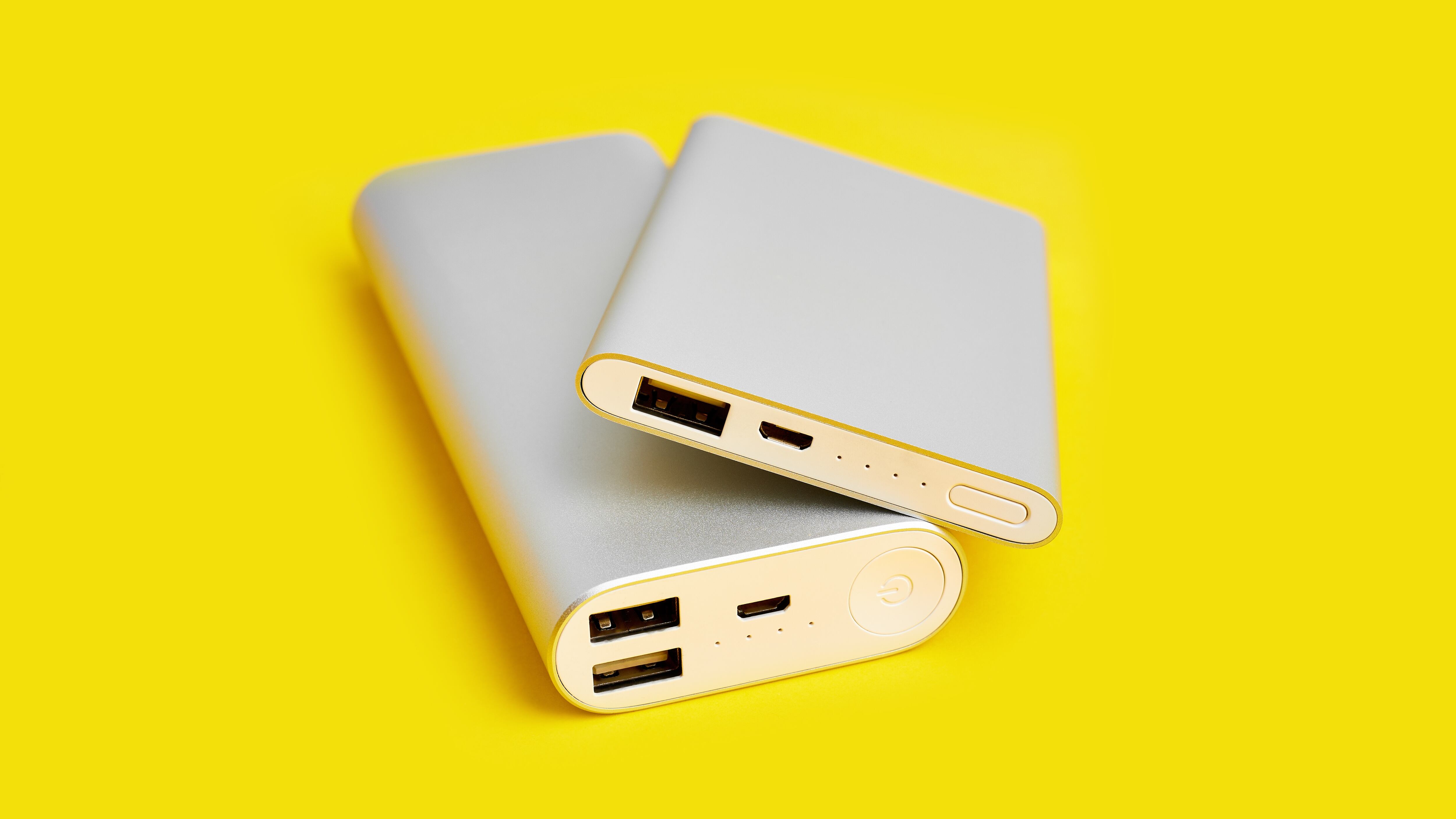 Power bank for charging mobile devices. White smart phone charger with power bank. Battery bank on a yellow background . External battery for mobile devices.