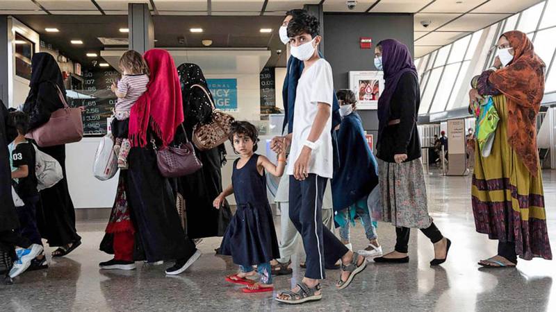 Refugees from Afghanistan are escorted to a waiting bus after arriving and being processed at Dulles International Airport in Dulles, Va., Aug. 23, 2021.
